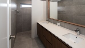 Une salle de bain moderne avec deux lavabos, un grand miroir et un espace douche.