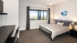 Une chambre moderne avec un grand lit, un bureau et une vue sur l’extérieur.