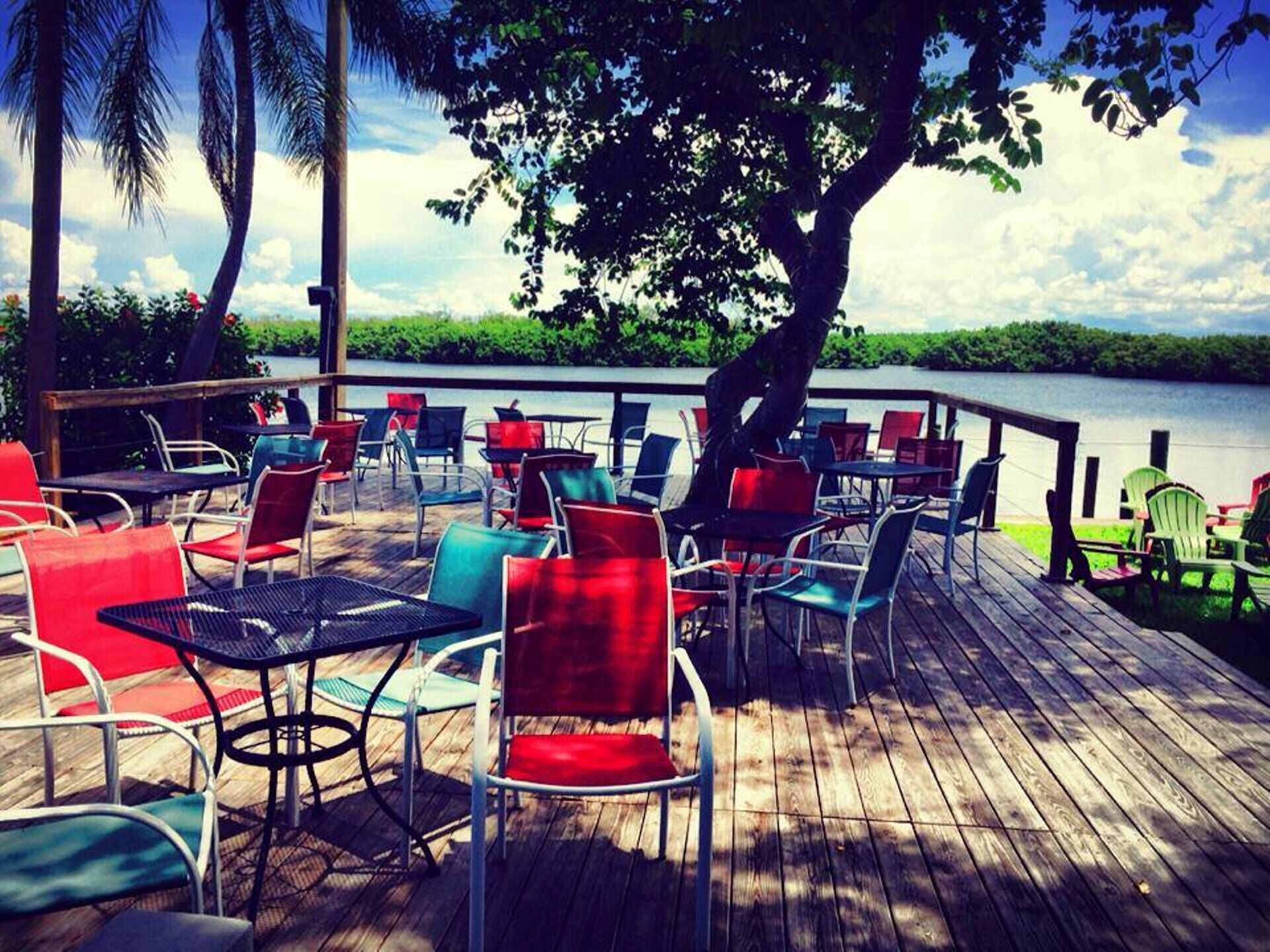 Une terrasse avec coin salon extérieur, comprenant des tables et des chaises, donnant sur un plan d’eau.