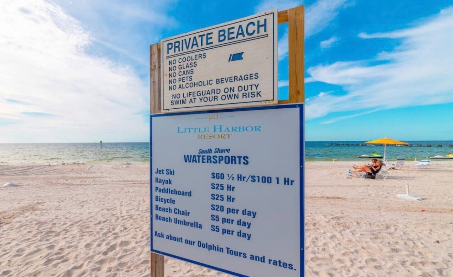 A beach sign with a list of prohibited items and a watersports rental sign for Little Harbor Resort.