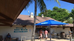 Een restaurant aan het strand met een bord waarop staat 
