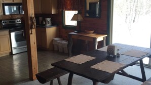 L’intérieur d’un chalet en bois comprend une cuisine, un coin repas et une grande fenêtre.
