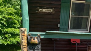 Une enseigne en bois portant l’inscription « BIENVENUE » et deux sculptures d’ours.