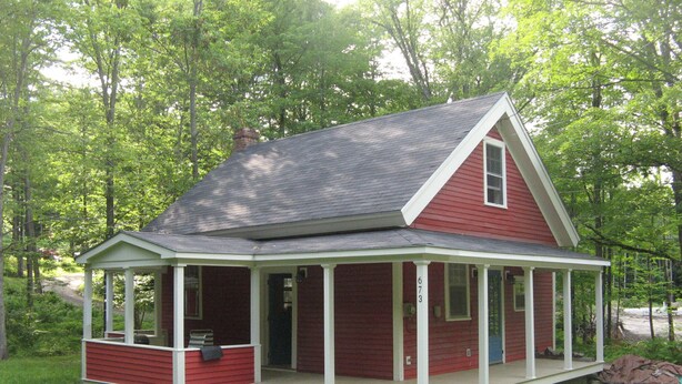 A red house with a covered porch and a chimney.