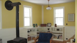 A living room with a wood-burning stove, a blue armchair, and a bookshelf.