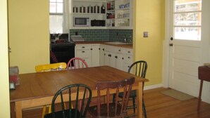 A kitchen with a wooden table and chairs, a microwave, and cabinets.