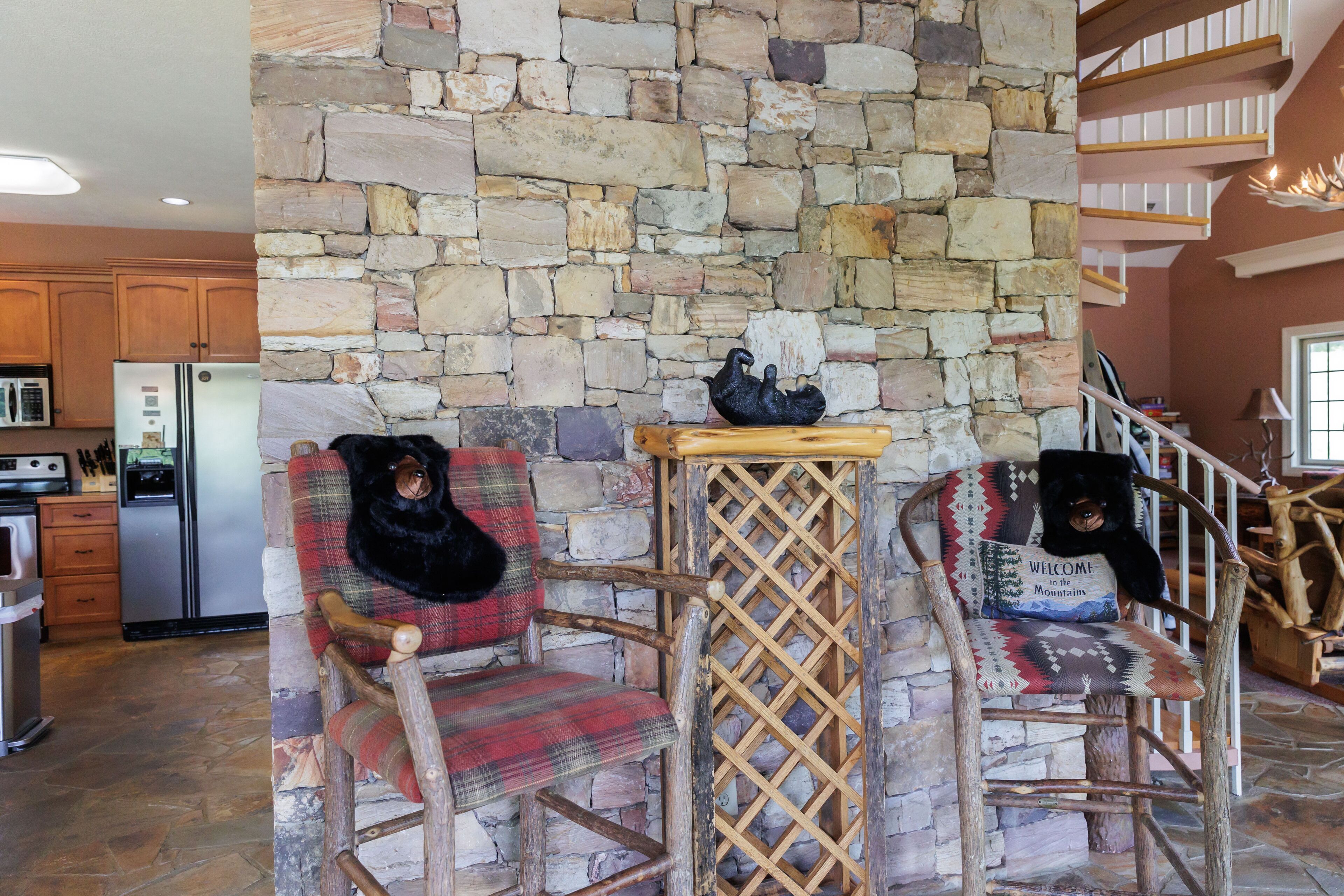 A rustic interior with stone walls, wooden chairs, and a kitchen area.