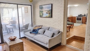 Un salon avec un canapé gris, une table basse en bois et un tableau accroché au mur.