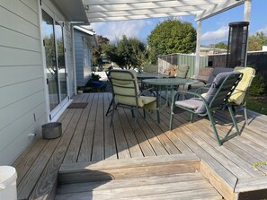 A covered patio with a wooden deck, metal table, and chairs. - Turangi town, cosy urban retreat with room for all, (Turangi)