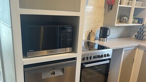 Een kleine keuken met een ingebouwde magnetron, vaatwasser en oven.
