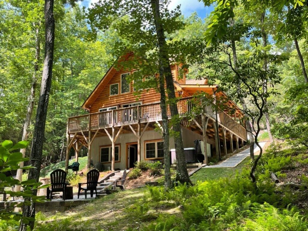 A cabin with a balcony, surrounded by trees.