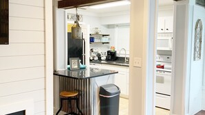 Une cuisine moderne avec des meubles blancs, un plan de travail noir et un plancher en bois.