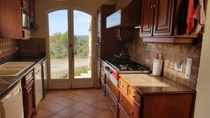 A kitchen with wooden cabinets, a stove, and a view through a glass door.