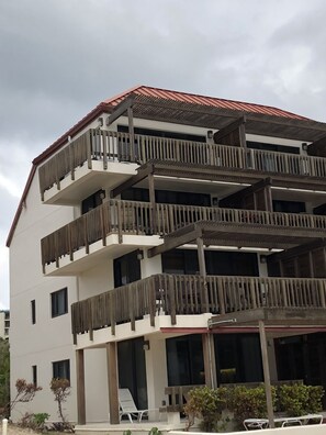 A multi-story building with balconies, a covered entrance, and a pool area. - Luxurious, Penthouse, 2 level, corner unit Oceanfront condo at Sapphire Beach (St Thomas)