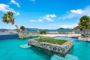 A pool area with clear blue water, stone walls, and lounge chairs. - Luxurious, Penthouse, 2 level, corner unit Oceanfront condo at Sapphire Beach (St Thomas)