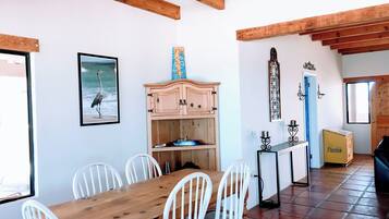 Un coin repas avec une table en bois et des chaises blanches, un buffet en bois et un tableau encadré au mur.
