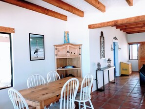 A dining area with a wooden table and white chairs, a wooden cabinet, and a framed picture on the wall. - PROMO-Beach Front on a Sandy Beach, Hi speed Wi-Fi- Gated community (San Felipe)