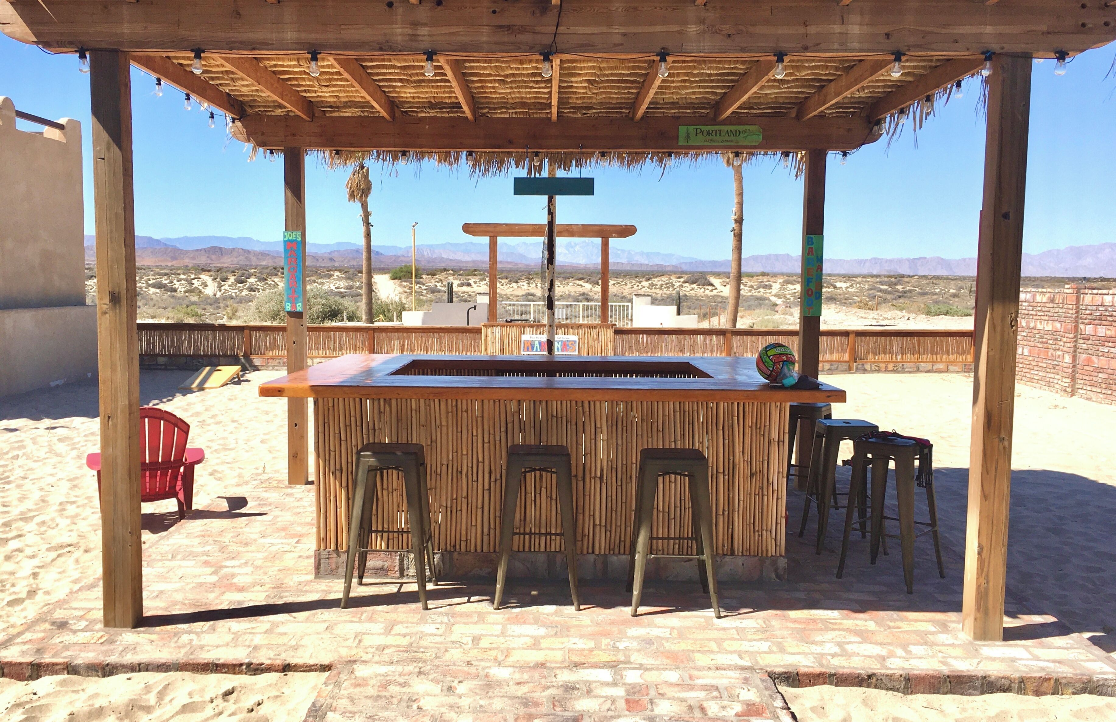 Un comptoir en bois avec des tabourets, une enseigne indiquant « Portland », et un paysage désertique en arrière-plan.