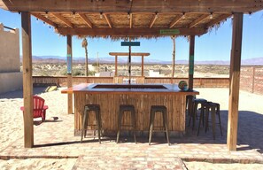 A wooden bar with stools, a sign indicating 'Portland', and a desert landscape in the background. - PROMO-Beach Front on a Sandy Beach, Hi speed Wi-Fi- Gated community (San Felipe)
