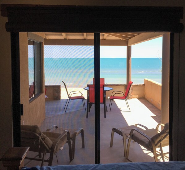 Un espace extérieur aménagé avec une table et des chaises, offrant une vue sur la plage.