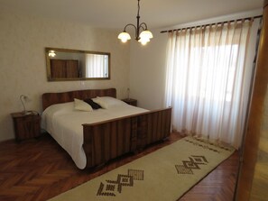 A bedroom with a wooden bed, a nightstand, a mirror, and a window with curtains. - Old renovated house with private swimming pool, romantic, quiet, family friendly (Labin)