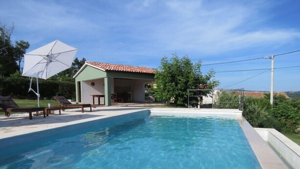 Piscina con sillas de descanso y un área de patio techada.