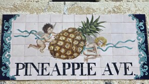 Un letrero con una piña y querubines, que dice 'PINEAPPLE AVE'.