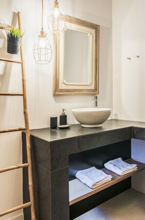 A modern bathroom with a large mirror, a vessel sink, a bamboo ladder, a towel rack, and a small potted plant. - Plaisance.  A 160 m2 apartment with exceptional view. (Athens)
