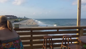 Une terrasse en bois offrant une vue sur une plage et l’océan.