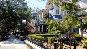 Une rue résidentielle bordée de maisons à deux étages, chacune dotée d’un porche et d’un balcon à l’avant.