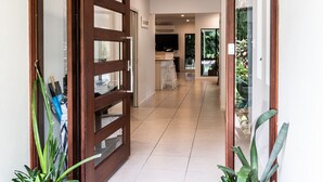 Ein moderner Eingangsbereich mit Glastür, Topfpflanzen und Fußmatte.