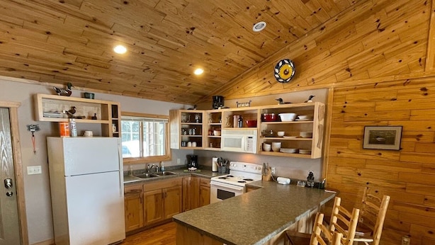 A compact kitchen with wooden cabinets, a refrigerator, a stove, and a sink.