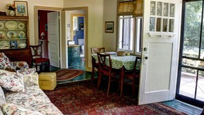 Un salón acogedor con un sofá floral, una mesa de comedor con sillas y una alfombra estampada.