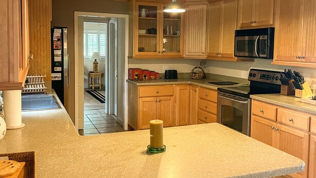 Una cocina con gabinetes de madera, encimera de granito, microondas y estufa.