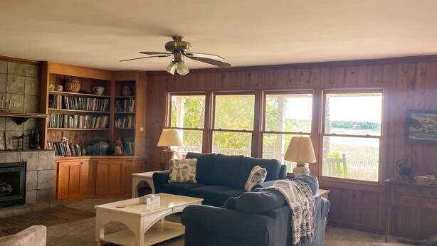 A cozy living room with a fireplace, a blue sofa, a coffee table, and a bookshelf.