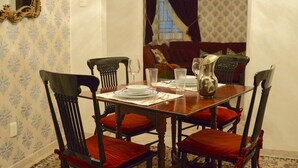 Une salle à manger avec une table en bois dressée pour quatre personnes, entourée de chaises dotées de coussins rouges.