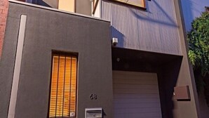 A modern two-story building with a garage door, a small window with blinds, and a mailbox. - Fitzgeorge - spacious home in inner Fitzroy Melbourne perfect location (Fitzroy)