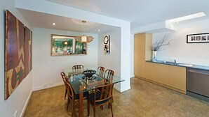A modern dining area with a glass table and wooden chairs, a kitchen with a sink and cabinets, and artwork on the walls. - Fitzgeorge - spacious home in inner Fitzroy Melbourne perfect location (Fitzroy)