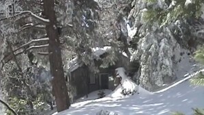 Een besneeerd landschap met bomen en een gebouw, deels bedekt met sneeuw.
