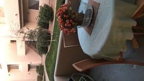 Ein Balkon mit Tisch, der mit einer weißen Tischdecke bedeckt ist, einem Korbwäscheschrank und einem Fahrrad.