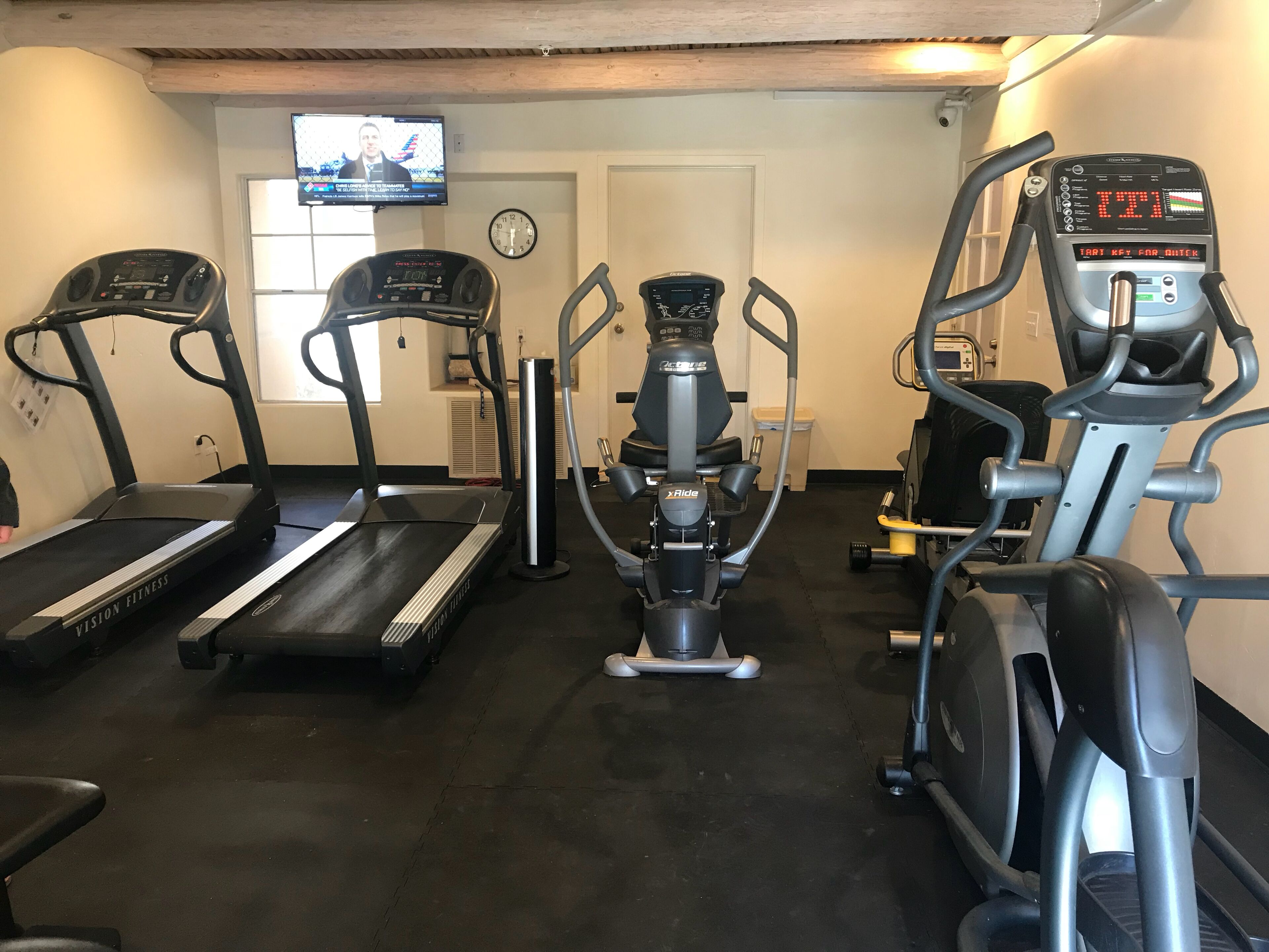 Ein Heimfitnessraum mit Laufbändern, einem Crosstrainer und einem stationären Fahrrad.
