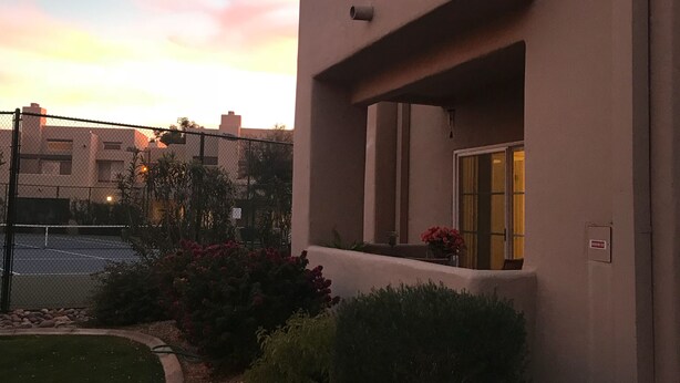 Ein modernes Gebäude mit flacher Fassade, einem kleinen Eingang mit einer Tür und einem Fenster mit Blick zum Himmel.