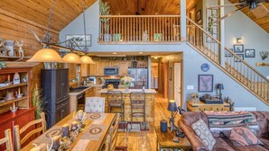 A spacious loft-style interior with a kitchen, dining area, and a staircase leading to an upper level.