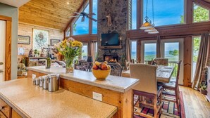 A spacious kitchen with a stone wall, wooden ceiling, and large windows.