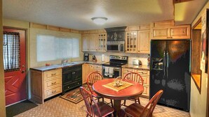 Une cuisine de taille réduite, dotée de meubles en bois, d’un réfrigérateur noir, d’une cuisinière et d’une table à manger avec des chaises.