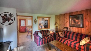 Un salon chaleureux avec un canapé à rayures, une table basse en bois et un téléviseur.