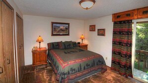 Une chambre à coucher avec un lit, deux tables de chevet avec des lampes, une fenêtre avec des rideaux et une porte.
