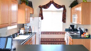 A kitchen with wooden cabinets, a refrigerator, a microwave, a stove, and a laptop on the counter. - Up-scale 3 Room Suite Located In A Popular SW Resort At @2900 Feet Elevation (Green Valley)