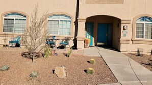 A building with a beige facade, arched windows, and a blue door. There are outdoor chairs and a small tree in front. - Up-scale 3 Room Suite Located In A Popular SW Resort At @2900 Feet Elevation (Green Valley)