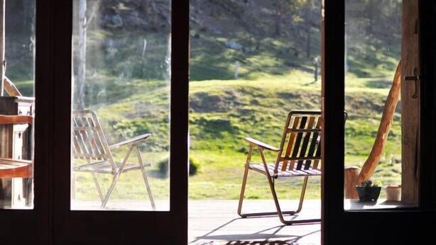 Una habitación con dos sillas mirando a un paisaje verde a través de una ventana.